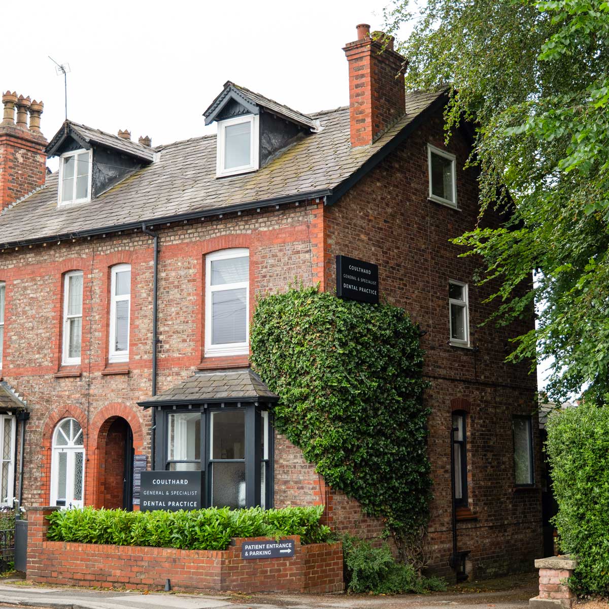 coulthard dental practice exterior. A 3 storey terraced house with dark signage and foliage crawling up the building